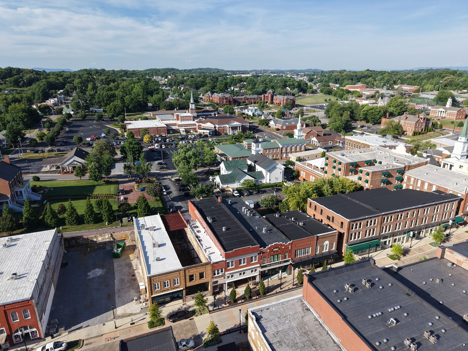 Aerial view of historic downtown Greeneville, Tennessee, with church steeples, brick storefronts, and mountains beyond