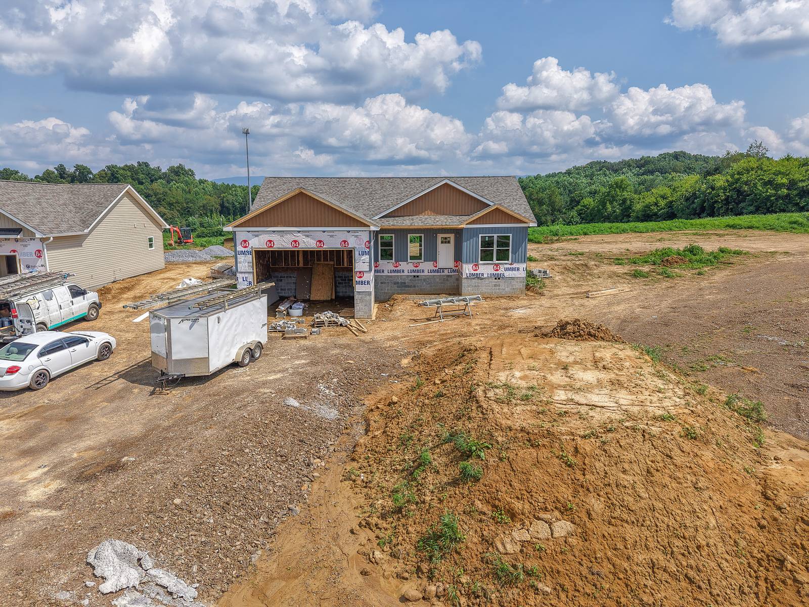 Bennett on Lot 5B in framing — board-and-batten siding going on, July 2026